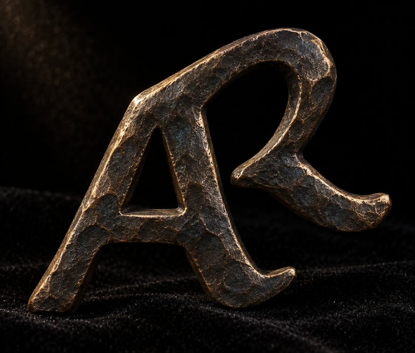 Monograma de Archon Atelier en metal oscuro con reflejos dorados